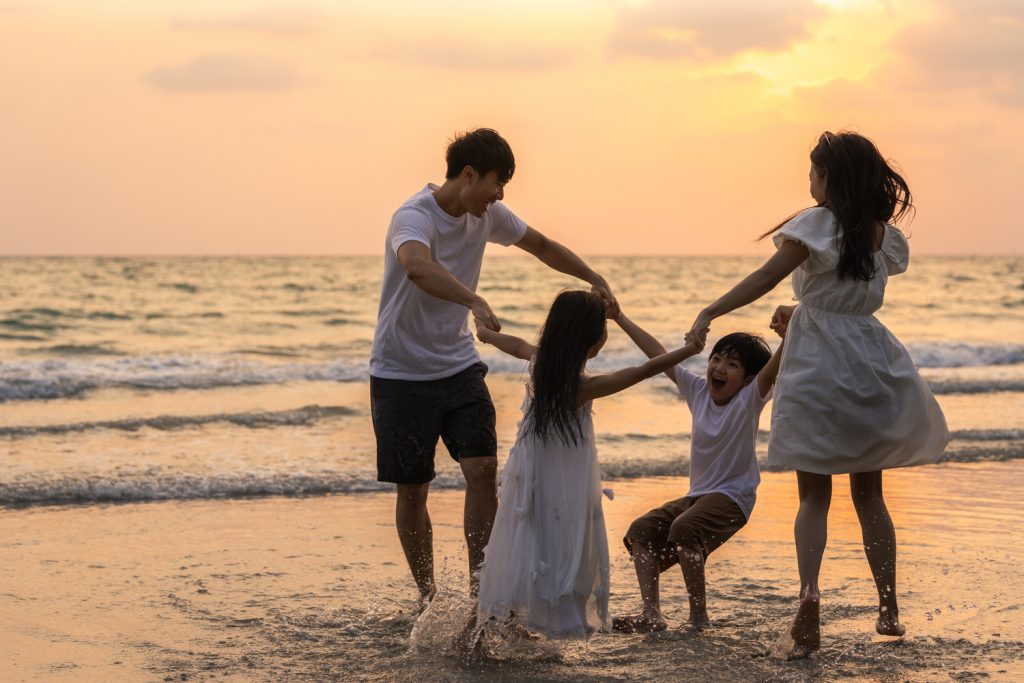 Sebuah keluarga kecil tengah menikmati kebersamaan di pantai pada sore hari (Sumber: tirachardz - Freepik)