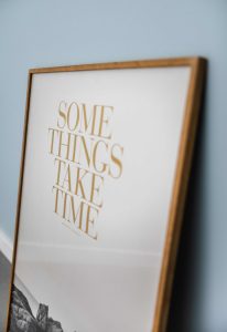 Pajangan dinding yang berbunyi "Somethings take time" yang berarti "Beberapa hal memerlukan waktu" (Photo by Duane Mendes on Unsplash)