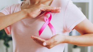 Seorang wanita yang menunjukkan pita merah muda sebagai tanda Kesadaran Kanker Payudara (Photo by Nattakorn Maneerat on Istock)