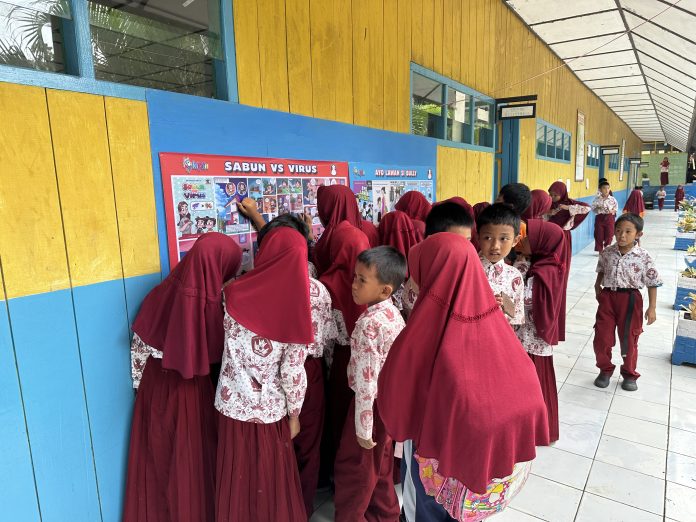 Siswa-siswi Sekolah Dasar tengah asik membaca mading atau majalah dinding berisi komik literasi Kipin