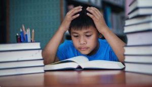 Ilustrasi seorang anak laki-laki kesulitan membaca dan memahami isi buku di hadapannya (Source: freepik.com)