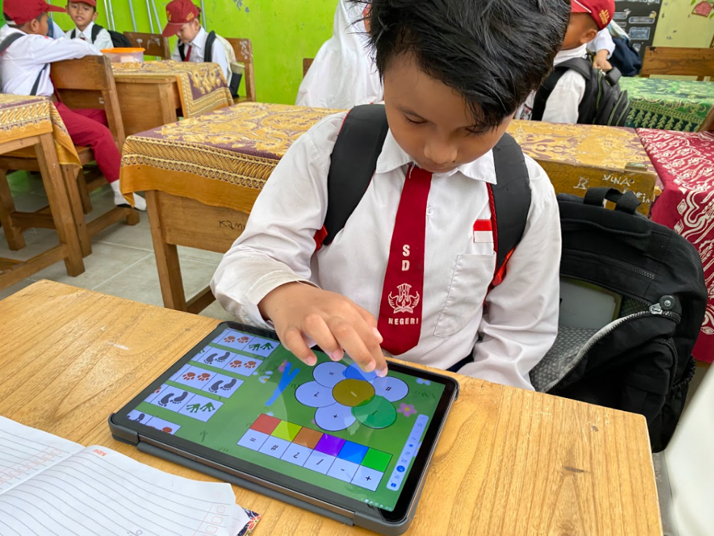 Seorang pelajar Sekolah Dasar (SD) sedang belajar menggunakan Buku Belajar Koding Kipin di tablet